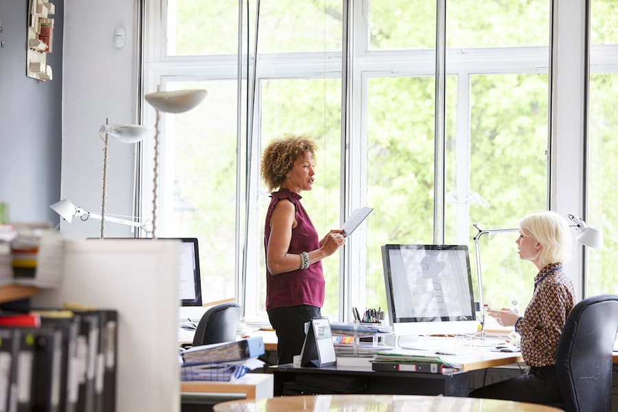 Two female interior designers discussing swatch at office desk