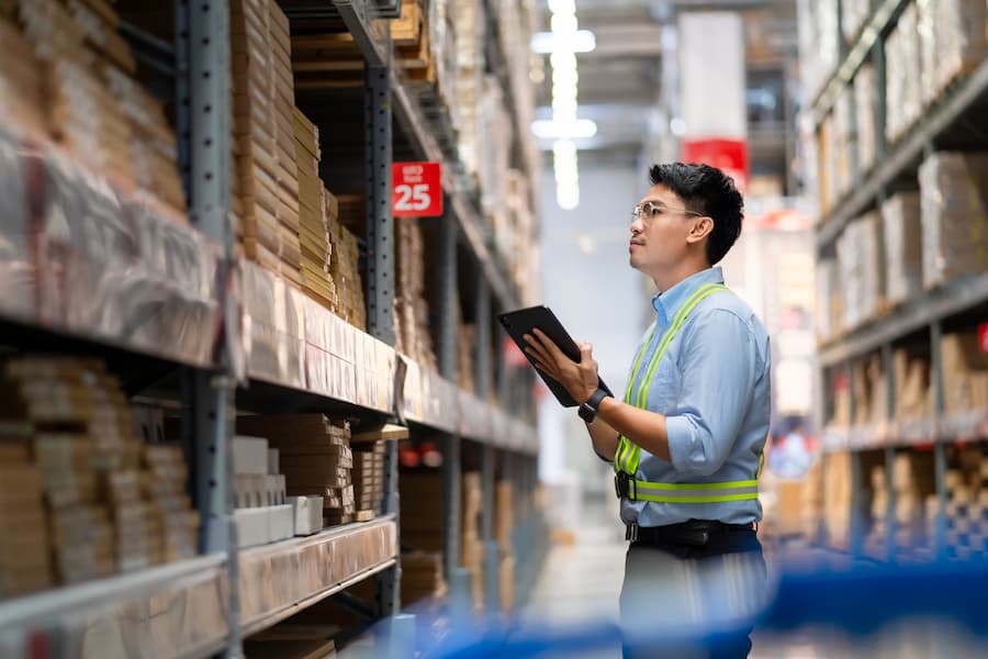 Inventory controller with tablet checking stock in warehouse's aisle