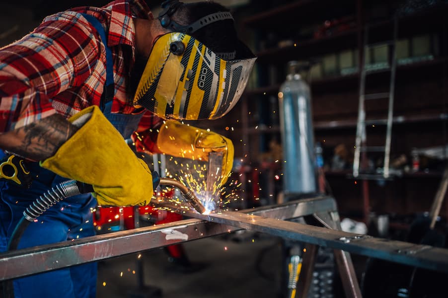 Welder Wearing Protective Gear Welding Metal in Workshop