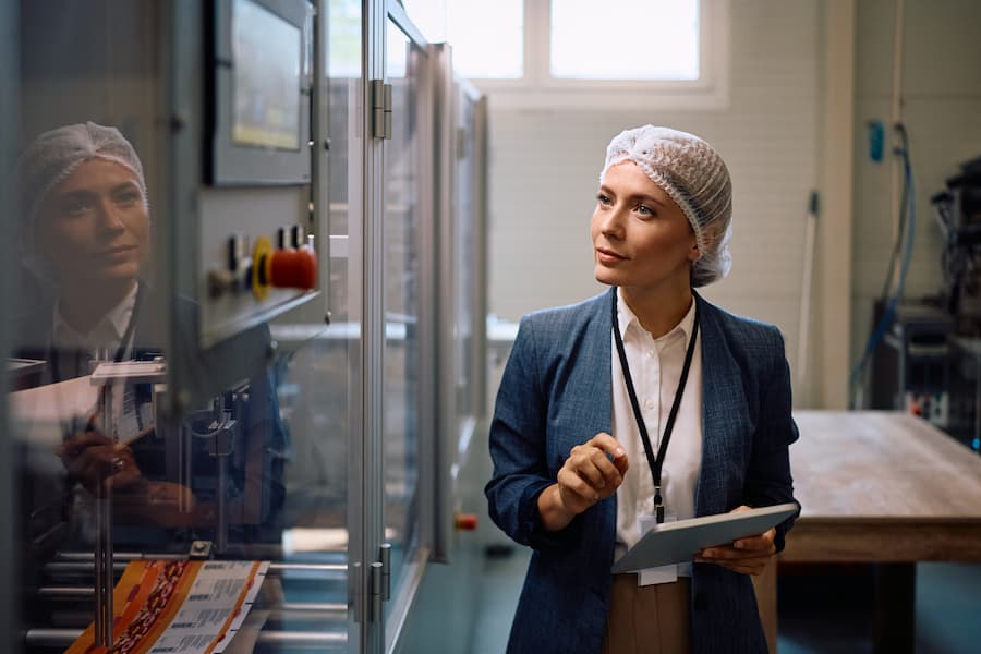 Woman Inspecting Food Packaging Production Line