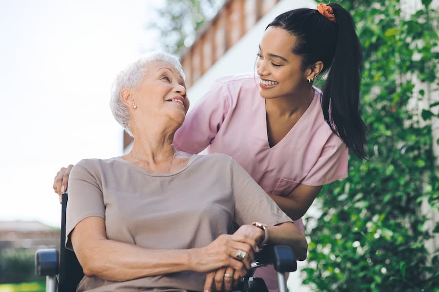 Woman Pushing Senior Woman in Wheelchair Outside
