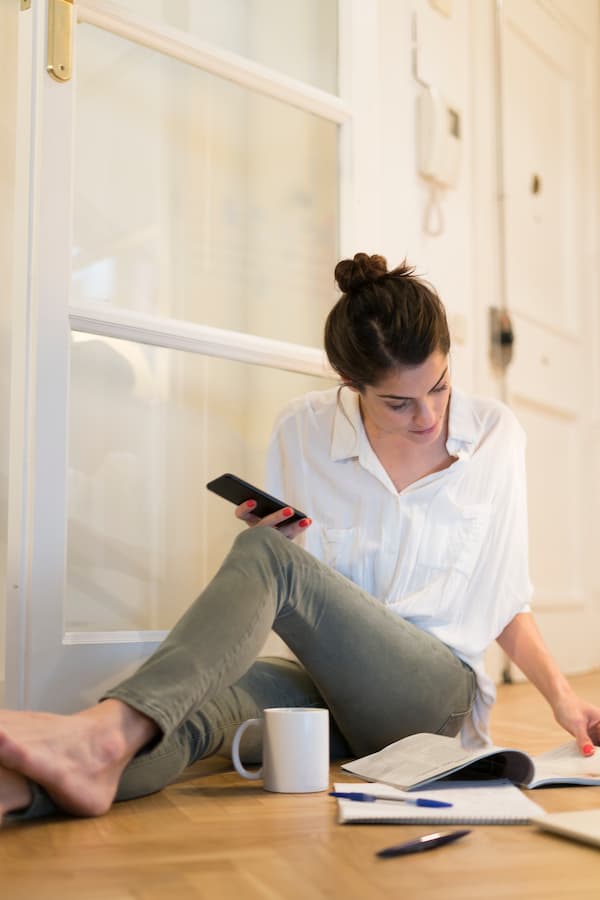Woman Relaxing at Home With Phone and Book