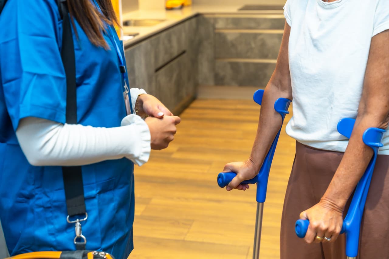 Woman With Crutches Consults With Health Professional Indoors