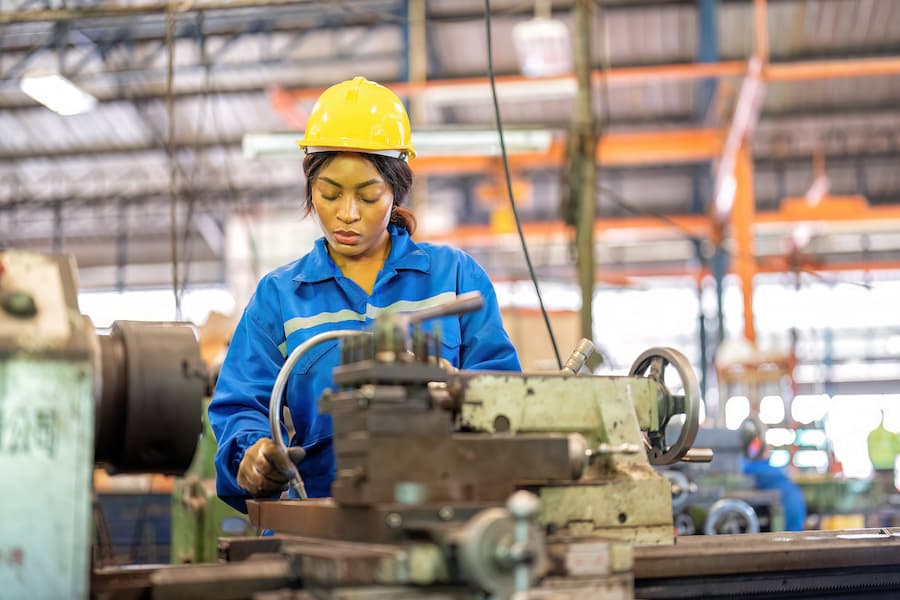 Woman worker in uniform operating machine at factory