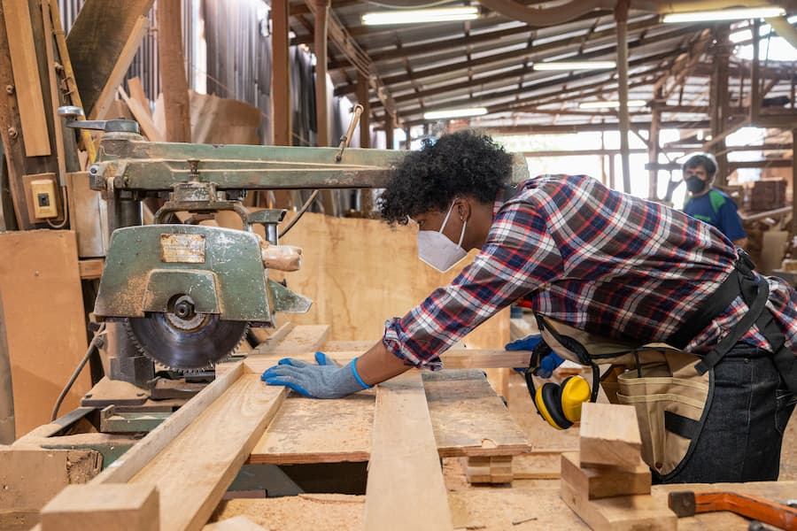 Woodworker Cutting Lumber with Saw in Workshop