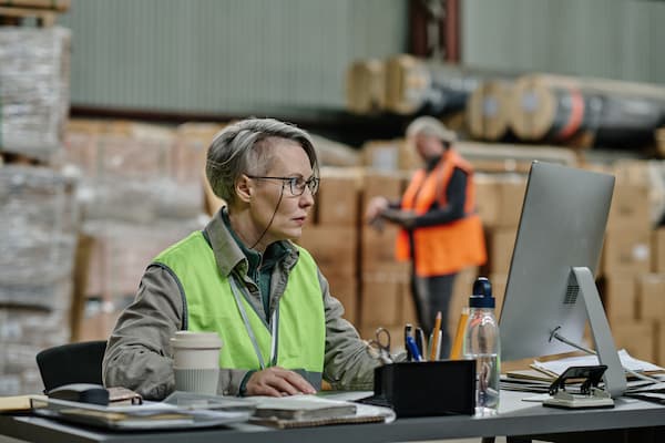Distribiuton coordinator working on computer in warehouse