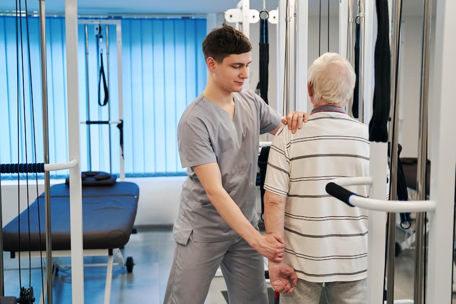 Young Adult Working With Senior at Rehabilitation Center