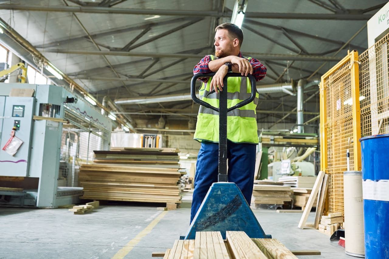 Young Material Handler Moving Boards in Warehouse