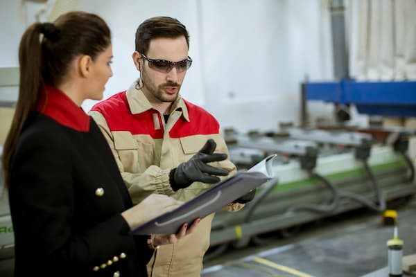 Young woman controlling process in the factory with male worker