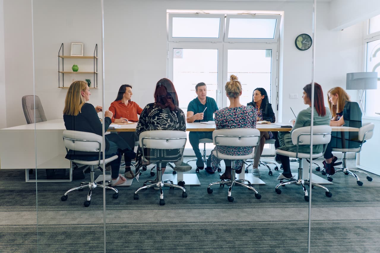 Diverse Business Team Discussing Projects in a Modern Glass Office.