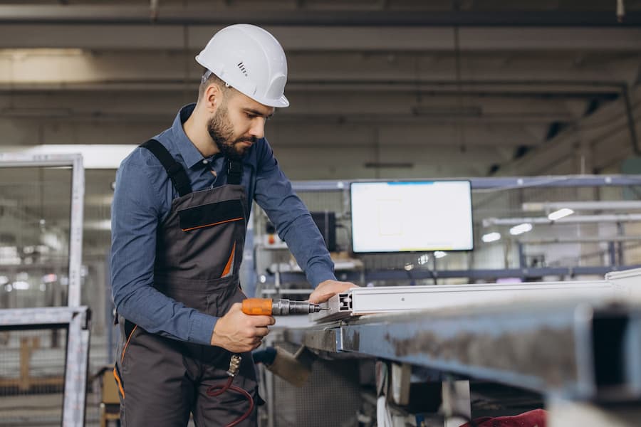Factory worker assembling aluminum and PVC window frames in production line