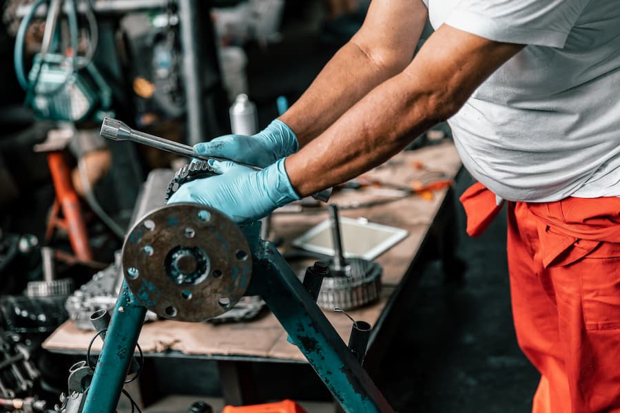 Mechanic Repairing Metal Component with Blue Gloves On