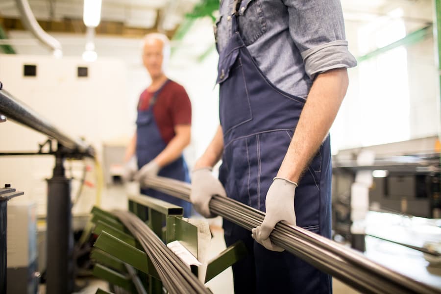 Metalwork Industry: Workers Handling Metal Rods Indoors