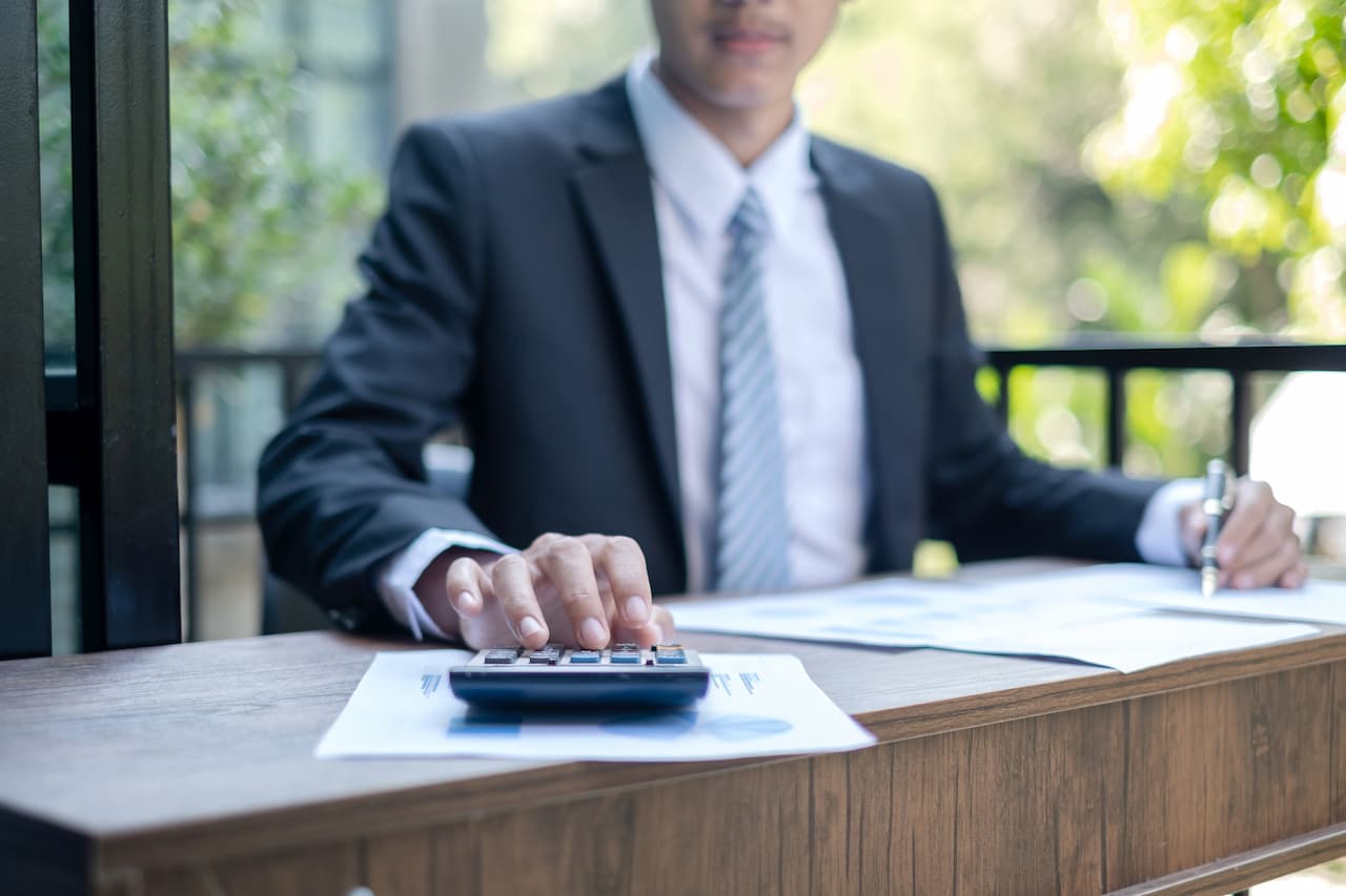 Businessman financial market analyst sits at their desks and calculate financial graphs