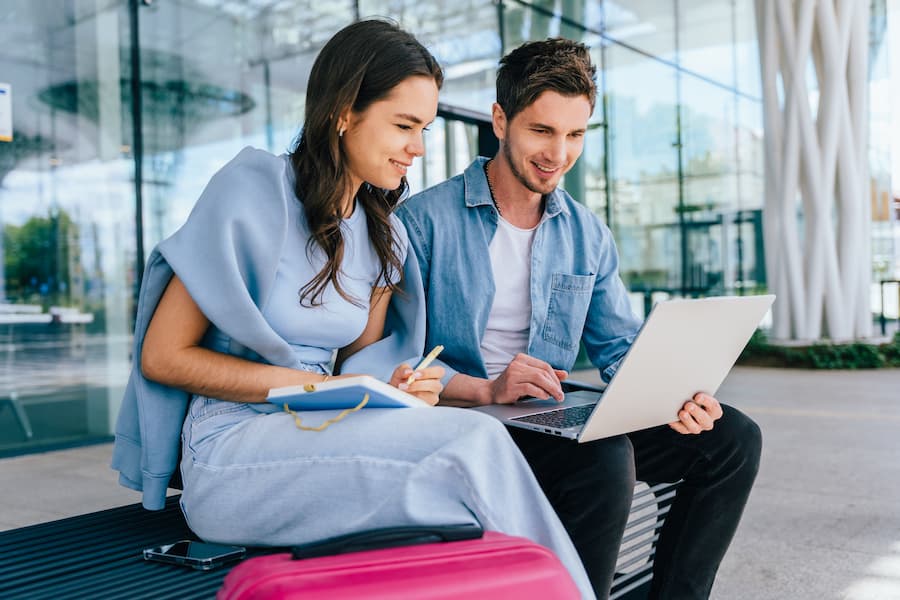 Smiling Woman and Man Working on Laptop Outdoors