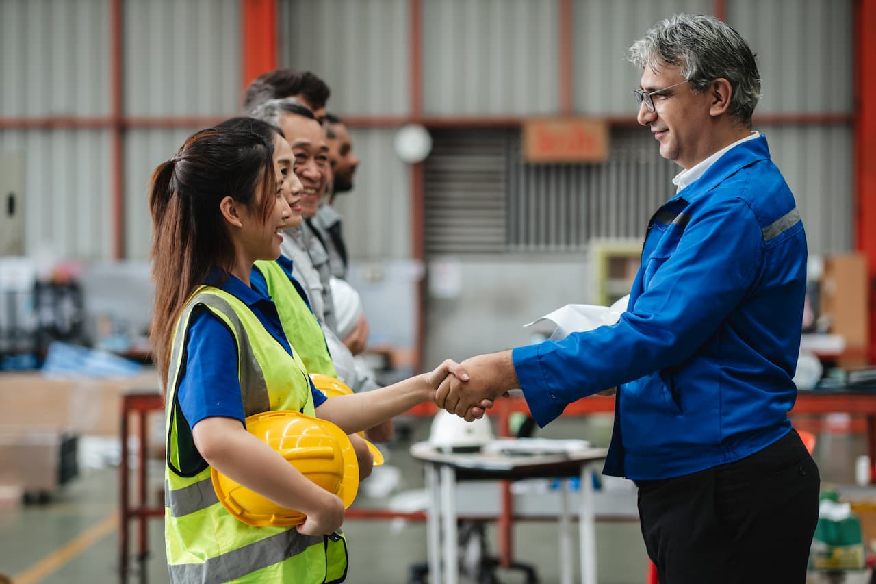 Team engineers and working holiday visa workers gather for a meeting at logistics warehouse
