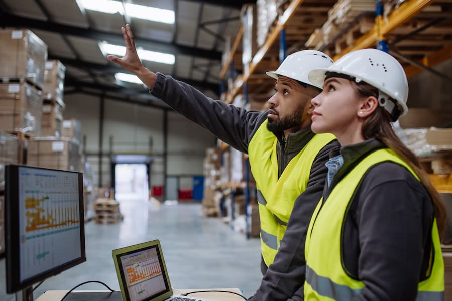 Warehouse manager talking with logistics employee in warehouse, planning transport of products