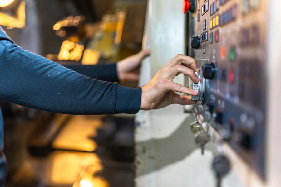 Worker using control panel of lathe machine in cnc factory