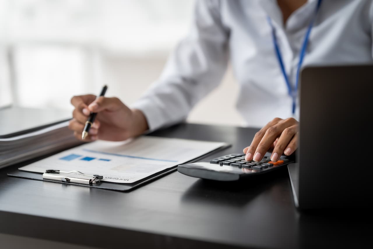 Closeup view of an accountant working with charts and calculator at office desk