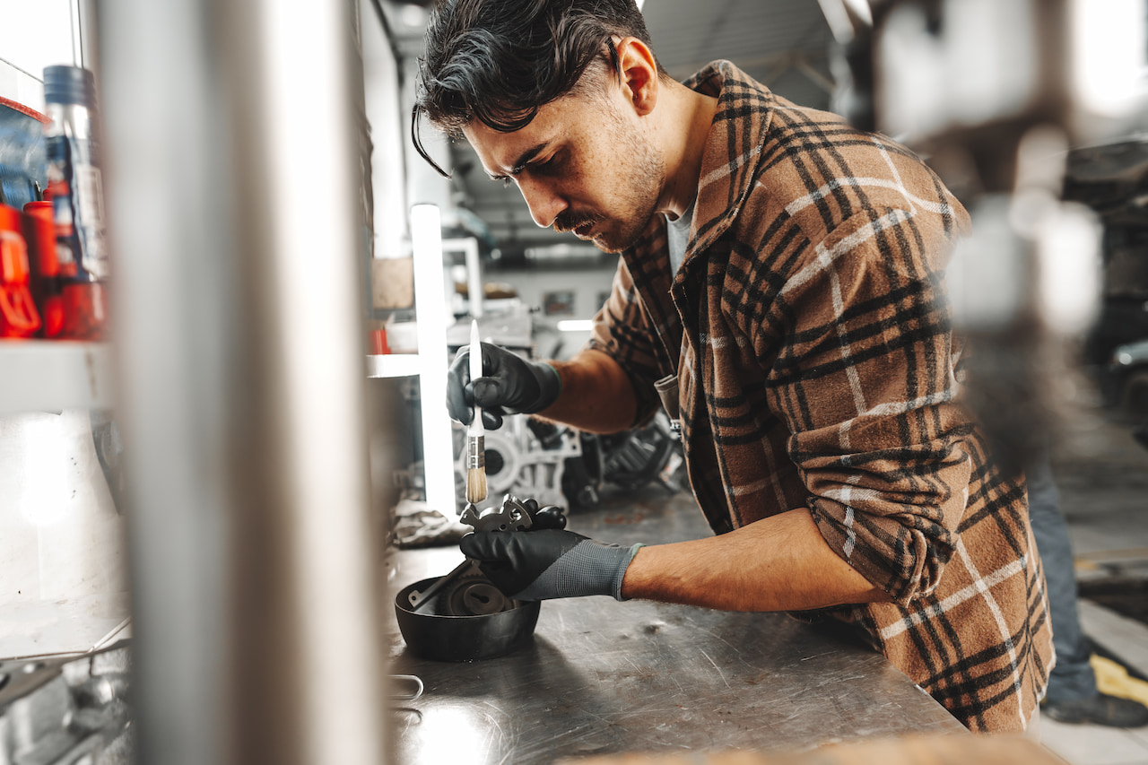 Young mechanic working on a car part in Brisbane workshop