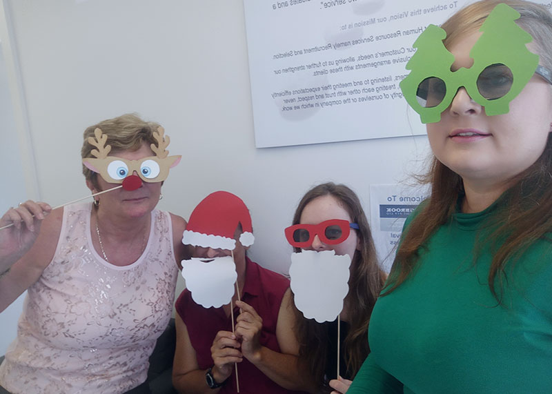 four people with Christmas photo booth props