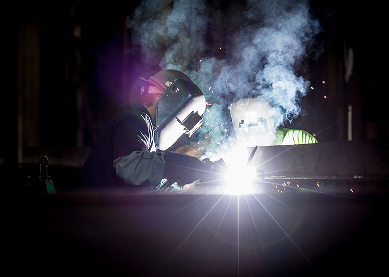 two welders with welding flash against black background